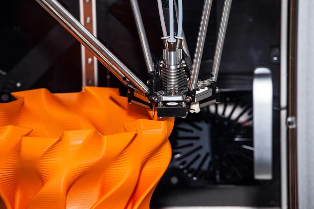 3D Printer fabricating an object out of orange plastic